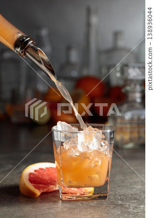 Grapefruit juice is poured into a glass with ice. 138936044