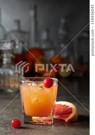 Cocktail with ice and grapefruit juice garnished with maraschino cherry. 138936045