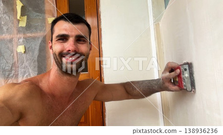POV of young man uses brush to clean finished wall surface removing dust and small imperfections after renovation work. Male worker carefully prepare smooth wall for next finishing stage inside room 138936236