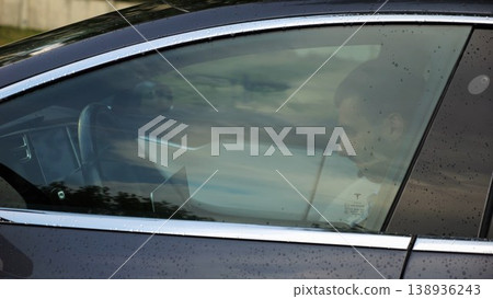 Young entrepreneur work on notebook while riding an autonomous self driving electric car at urban road. Male businessman type text on laptop during ride on electrical vehicle with autopilot after rain Young entrepreneur work on notebook while riding an autonomous self driving electric car at urban road. Male businessman type text on laptop during ride on electrical vehicle with autopilot after rain 138936243
