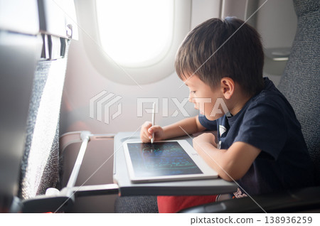5 Year Old Boy Engaged in Creative Drawing on a Tablet While Traveling in an Airplane 5 Year Old Boy Engaged in Creative Drawing on a Tablet While Traveling in an Airplane 138936259