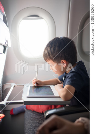 5 Year Old Boy Engaged in Creative Drawing on a Tablet While Traveling in an Airplane 138936260
