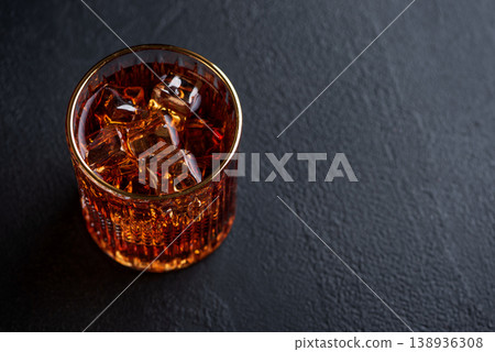 Whiskey Glass with Ice on Wooden Coaster against Dark Concrete Background Whiskey Glass with Ice on Wooden Coaster against Dark Concrete Background 138936308