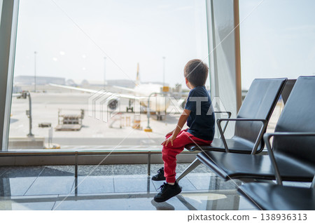 Young Boy Watching Airplane at Airport Terminal Window Young Boy Watching Airplane at Airport Terminal Window 138936313