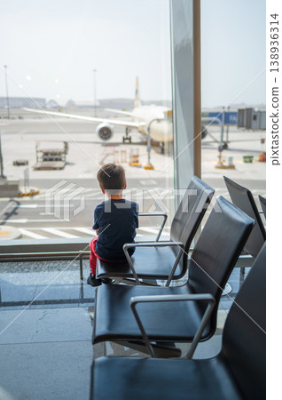 Young Boy Watching Airplane at Airport Terminal Window Young Boy Watching Airplane at Airport Terminal Window 138936314