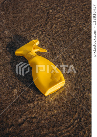 Yellow sunscreen spray bottle lying in shallow sea water on sandy beach Summer sun protection concept minimal product mockup 138936417