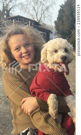 Child Joyfully Holding Puppy in Outdoor Setting 138936514