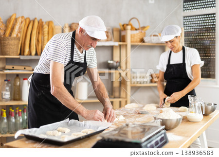 Elderly man and woman make and fold pieces of dough Elderly man and woman make and fold pieces of dough 138936583