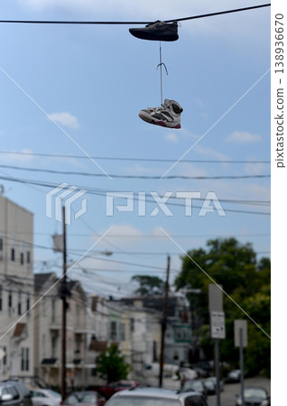 City Shoes Scene. Casual Sneakers Dangle Over Quiet Urban Neighborhood Under Clear Blue Sky City Shoes Scene. Casual Sneakers Dangle Over Quiet Urban Neighborhood Under Clear Blue Sky 138936670