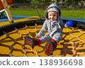 Little girl in sunglasses sits on a rope swing at the playground 138936698