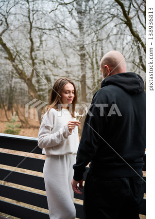 Man and woman toasting with sparkling wine on terrace overlooking trees, enjoying calm moment together, symbolizing intimacy, lifestyle and seasonal getaway experience 138936813