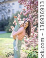 Trendy mom with her little daughter under blooming magnolia trees in a Prague park. Capturing a stylish family moment with a modern approach to parenting 138936913