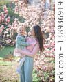 Young mother with her little daughter in a blooming magnolia garden in Prague. Symbol of maternal love and the beauty of springtime bonding in nature 138936919
