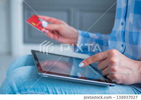 Woman using black tablet and red credit card for online shopping at home Woman using black tablet and red credit card for online shopping at home 138937027