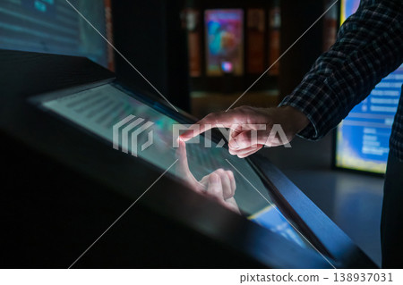 Man using interactive touchscreen display at modern museum or exhibition 138937031