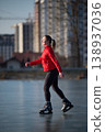 Female skater enjoying calm winter day on urban lake ice with copy space around her. Useful for advertising layouts, recreation concepts, fitness content or editorial design 138937036
