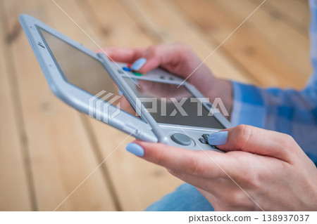 Woman using grey portable game console Woman using grey portable game console 138937037