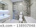 Bright bathroom interior with bathtub, sink vanity and toilet in gray stone finish. Contemporary washroom with rainfall shower, heated towel rail, lighted mirror and sleek design 138937048