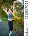 Woman raising arms and celebrating after run. Happy female in sportswear on park path, outdoor fitness, success, achievement, active lifestyle, energy and motivation concept 138937055