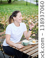 Woman savoring dessert at street cafe table. Female athlete in sportswear enjoying coffee break after exercise, indulgence, relaxation, lifestyle balance and reward concept 138937060