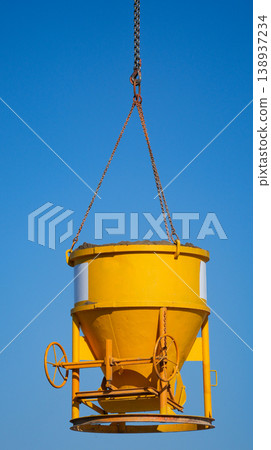 Yellow concrete pouring bucket lifted by crane at the building construction site. Yellow concrete pouring bucket lifted by crane at the building construction site. 138937234