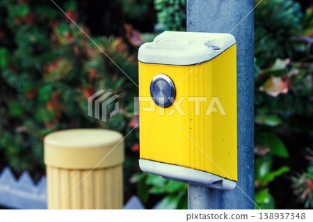 Close up of a yellow pedestrian crossing push button mounted on a pole. Urban street infrastructure Close up of a yellow pedestrian crossing push button mounted on a pole. Urban street infrastructure 138937348