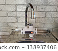 Hot water flows from the tap. Instant kitchen water heater with display and RCD 138937406