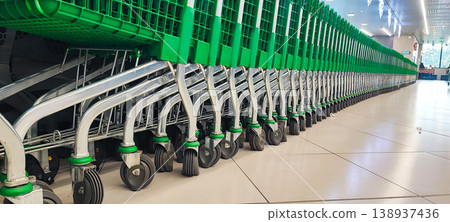 A row of shopping carts lined up inside a supermarket. Concepts of consumer behavior, retail industry, and everyday shopping convenience. 138937436