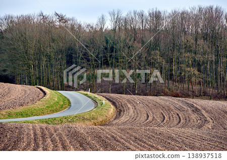 The landscape of farm land and tall green trees near a curvy road with a blue sky. Beautiful view of plowed ground near a forest and roadway on a winter day. Tidy and well maintained field outdoors The landscape of farm land and tall green trees near a curvy road with a blue sky. Beautiful view of plowed ground near a forest and roadway on a winter day. Tidy and well maintained field outdoors 138937518