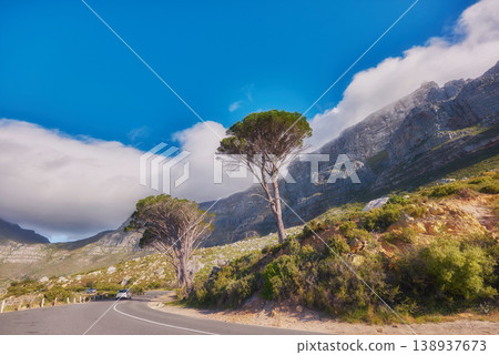 Countryside road by winding through the mountains on a scenic day. Street on the mountain with green trees and cloudy blue sky copy space. A nature path for traveling or hiking in Cape Town 138937673