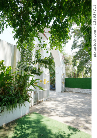 a white wall with a gate and trees a white wall with a gate and trees 138937713