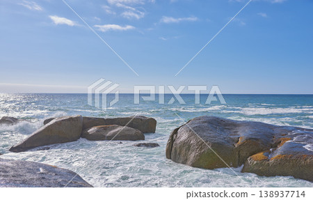 Big rocks in the ocean or sea water with a blue sky background. Beautiful landscape with a scenic view of the beach with boulders on a summer day. Relaxing scenery of the seaside or nature Big rocks in the ocean or sea water with a blue sky background. Beautiful landscape with a scenic view of the beach with boulders on a summer day. Relaxing scenery of the seaside or nature 138937714