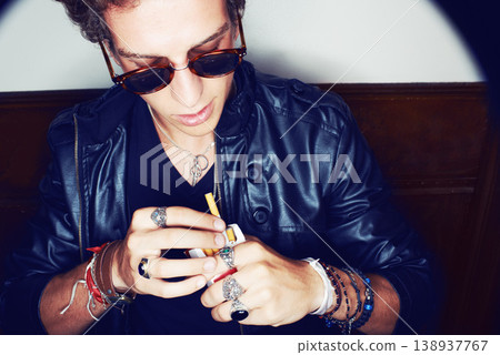 Man with cigarette in hand, grunge fashion and rockstar attitude on white background in spotlight. Cool punk style, rebel and smoking, confident and handsome male model in studio with sunglasses. Man with cigarette in hand, grunge fashion and rockstar attitude on white background in spotlight. Cool punk style, rebel and smoking, confident and handsome male model in studio with sunglasses. 138937767