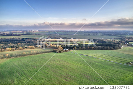 Serene landscape of endless grass fields with trees in the peaceful and quiet countryside against vibrant blue horizon with copy space. Aerial view of rural farm land on a cloudy summer day in Europe Serene landscape of endless grass fields with trees in the peaceful and quiet countryside against vibrant blue horizon with copy space. Aerial view of rural farm land on a cloudy summer day in Europe 138937781