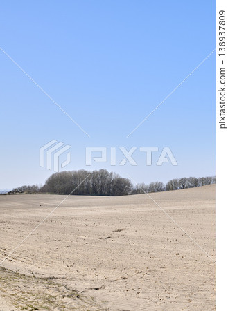 Barren farm land with trees and blue sky background. A desolate agricultural farmland caused by summer heat droughts and impact on agriculture industry. Open and empty dry sand field with copy space Barren farm land with trees and blue sky background. A desolate agricultural farmland caused by summer heat droughts and impact on agriculture industry. Open and empty dry sand field with copy space 138937809