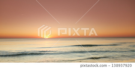 Seascape and landscape of a beautiful orange sunset on the west coast of Jutland in Loekken, Denmark. Sun setting on the horizon on an empty beach at dusk over the ocean and sea at night 138937920