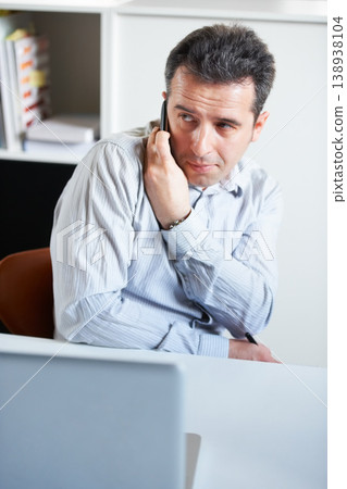 Businessman, phone and secret call in office private information, confidential or sneaky discussion. Male person, mobile or talk at laptop for inside trade, crime job or company online security break 138938104