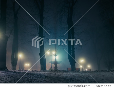 Big fontaine of a night winter park in a fog. Footpath in a fabulous winter city park at night in fog with benches and patterns. Beautiful foggy evening in the Mariinsky Park. Kyiv, Ukraine. 138938336