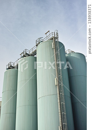 Silo storage tankers against a gray sky in Danish oil industry. large oil plant storage tanks for export in industrial area. Silo tankers for keeping bulk food products, substances and materials safe Silo storage tankers against a gray sky in Danish oil industry. large oil plant storage tanks for export in industrial area. Silo tankers for keeping bulk food products, substances and materials safe 138938371