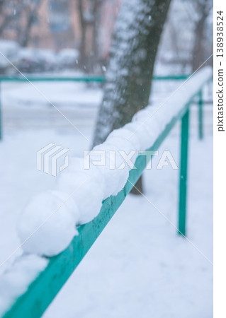 Snowballs lie in a row on a green hedge. Snow is falling. Winter 138938524