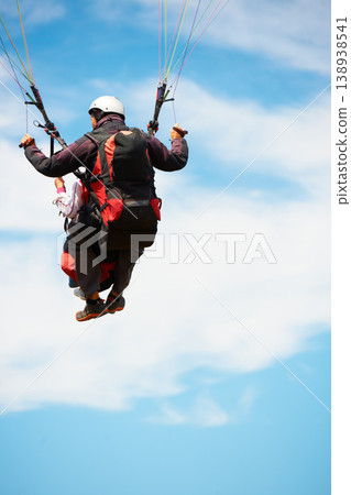 People, paragliding and freedom in sky, nature and extreme sport with back for fitness. Coach, partnership and person with adventure, helmet and fearless with backpack, parachute and jump with safety 138938541