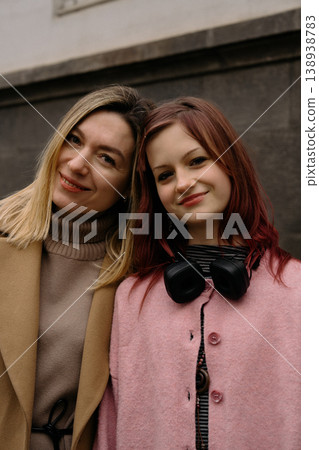 Mother and daughter smiling together in the city, enjoying a moment outdoors in cool weather Mother and daughter smiling together in the city, enjoying a moment outdoors in cool weather 138938783
