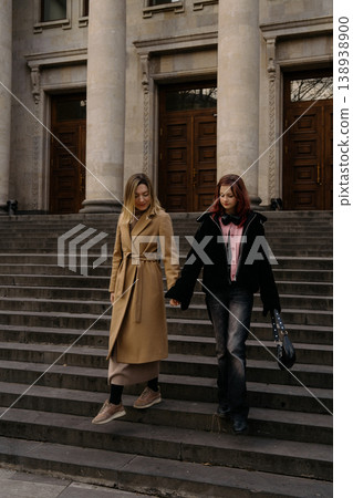 Mother and teenage daughter walking together down steps in front of a large building Mother and teenage daughter walking together down steps in front of a large building 138938900