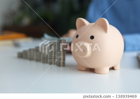 Growing money stacks and piggy bank on the table. Financial planning concept symbolizing saving and investment growth. 138939469