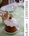 Easter cake with icing and decorations on green tablecloth with rabbits and glasses nearby 138939866