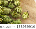 Dried hop cones are placed on a wooden table, conveying the aroma and bitterness of hops used as an ingredient in beer brewing. 138939910