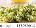 Dried hop cones are placed on a wooden table, conveying the aroma and bitterness of hops used as an ingredient in beer brewing. 138939911