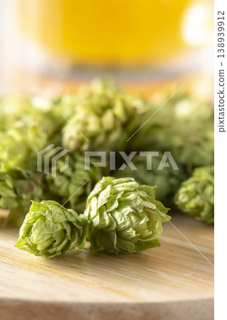 Dried hop cones are placed on a wooden table, conveying the aroma and bitterness of hops used as an ingredient in beer brewing. Dried hop cones are placed on a wooden table, conveying the aroma and bitterness of hops used as an ingredient in beer brewing. 138939912