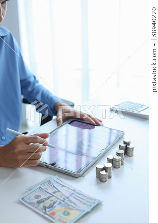 Close-up hand using digital tablet for tracking or analyzing financial data for budgeting and planning. Close-up hand using digital tablet for tracking or analyzing financial data for budgeting and planning. 138940220