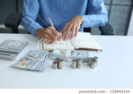 Three stacks of coins arrange separated on the table while businessman writing in a notebook. Financial planning and wealth accumulation for retirement or future investment. Three stacks of coins arrange separated on the table while businessman writing in a notebook. Financial planning and wealth accumulation for retirement or future investment. 138940344